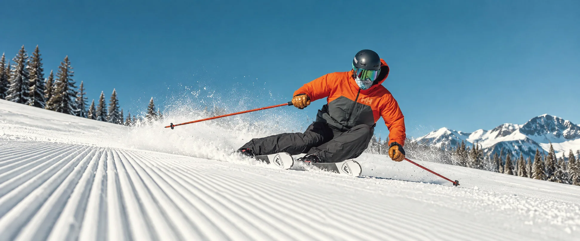 A skier carving a turn on freshly groomed corduroy under a clear blue sky